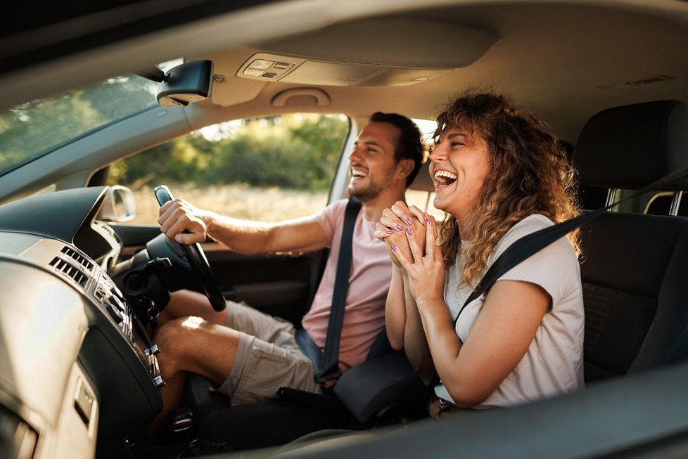 A happy couple driving their new car